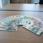 Gros plan sur des billets en euros disposés en demi-cercles sur une table, illustrant des salaires et le smic roumain.